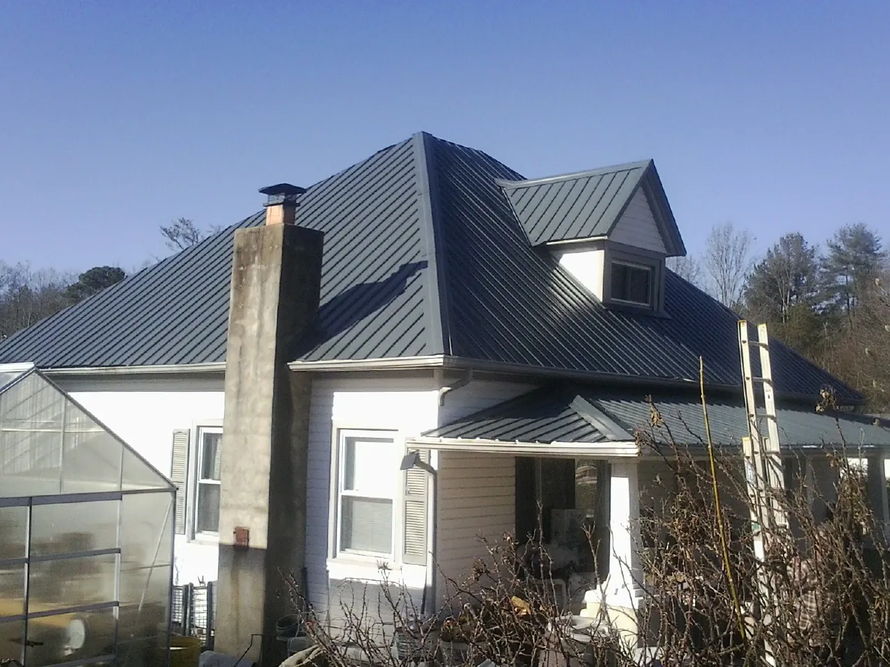 Dark blue standing seam metal roof on a white farmhouse with dormer — Slate & Tile Roof Repair by Roofing Brothers in Lonedell