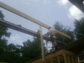 Carpenter setting a ridge beam over a new addition frame — Ice Dam Removal by Roofing Brothers in Lonedell
