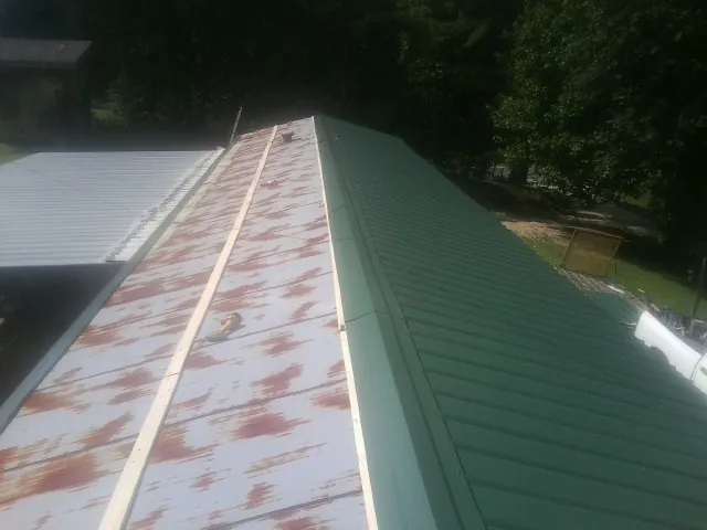 Old rusted panels beside newly installed green metal roofing — Wind Damage Roof Repair by Roofing Brothers in Lonedell