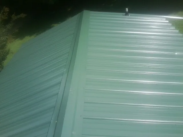 New green metal panels meeting at the ridge of a roof — Flat Roof Repair work by our crew in Lonedell