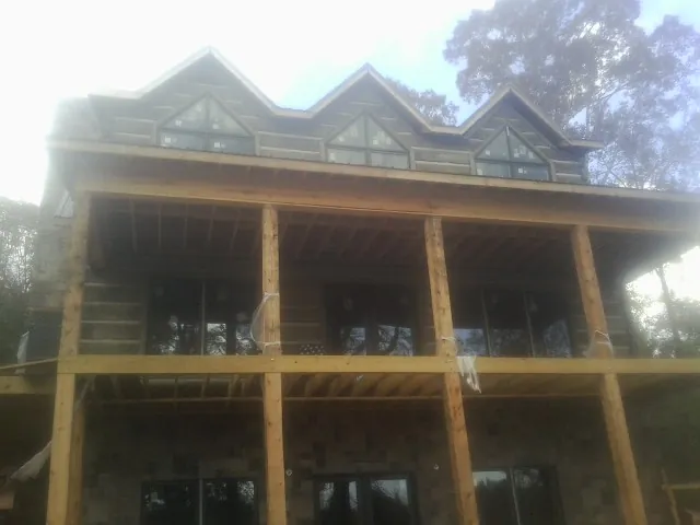 Dormers and porch framing on a large log home under construction — Roof Coating work by our crew in Lonedell